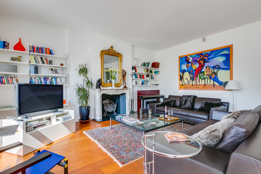 Large eclectic formal enclosed living room in London with white walls, medium hardwood floors, orange floor, a standard fireplace, a concrete fireplace surround and a freestanding tv.