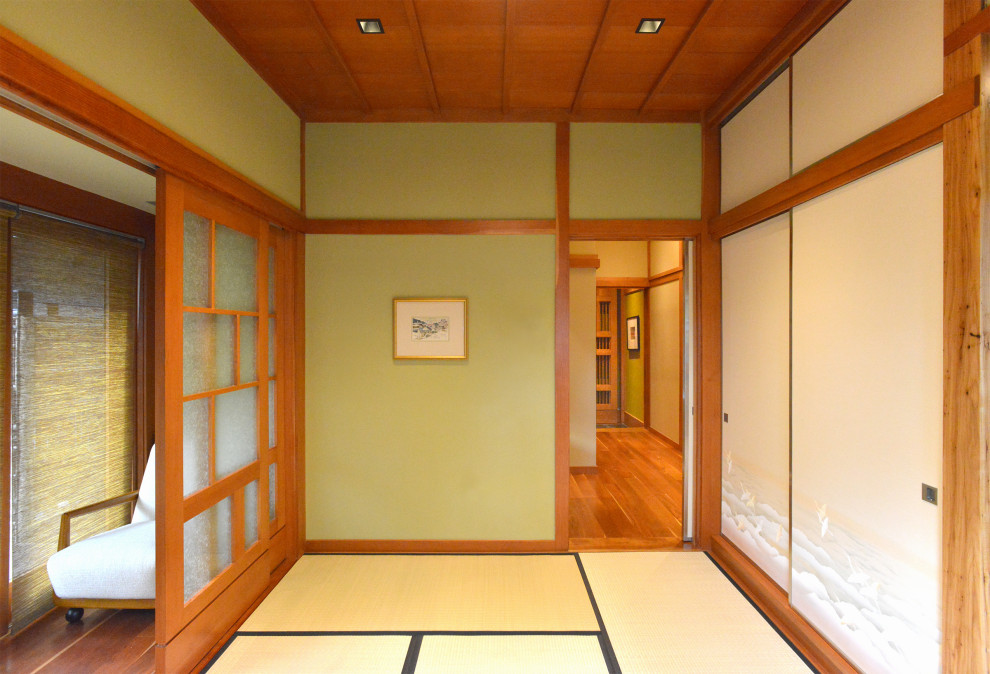 Photo of a mid-sized asian guest bedroom in Austin with tatami floors, beige floor, wood and green walls.