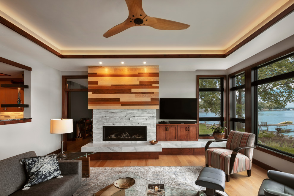 Design ideas for a contemporary open concept living room with light hardwood floors, a standard fireplace, a tile fireplace surround, a freestanding tv and recessed.