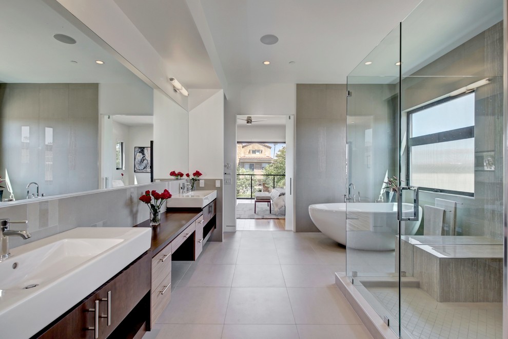 Design ideas for a contemporary master bathroom in Orange County with a freestanding tub, a corner shower, flat-panel cabinets, dark wood cabinets, gray tile and white walls.