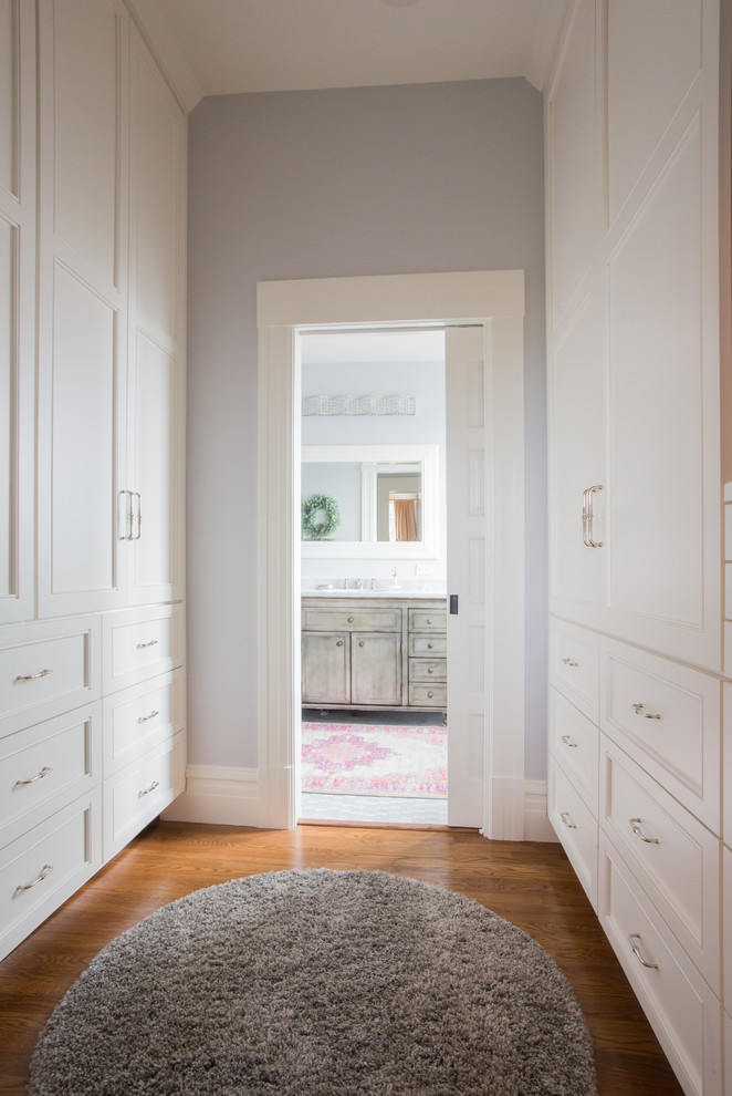 This is an example of a traditional gender-neutral walk-in wardrobe in San Francisco with recessed-panel cabinets, white cabinets, dark hardwood floors and brown floor.