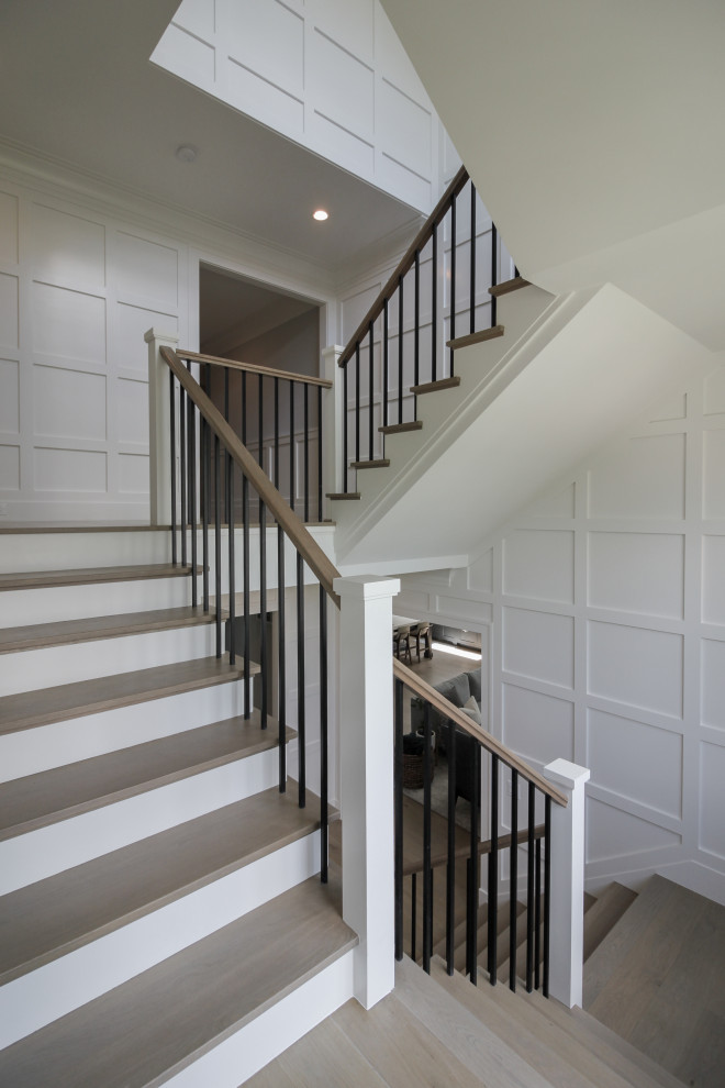 Aménagement d'un grand escalier classique en U avec des marches en bois, des contremarches en bois, un garde-corps en bois, boiseries et palier.