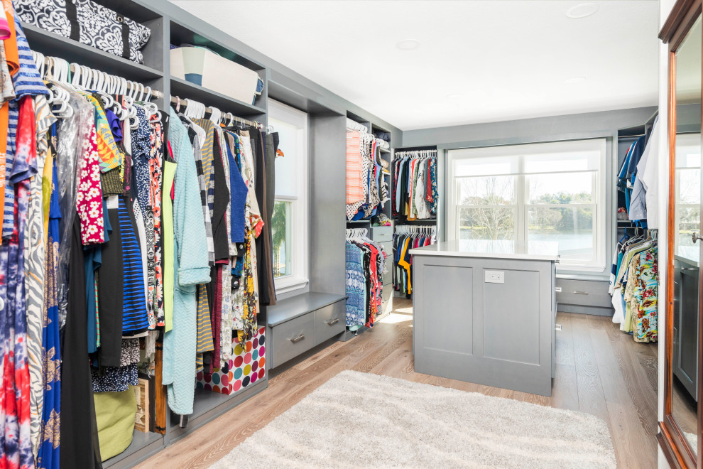 This is an example of an expansive transitional gender-neutral walk-in wardrobe in Orlando with recessed-panel cabinets, grey cabinets, vinyl floors and brown floor.