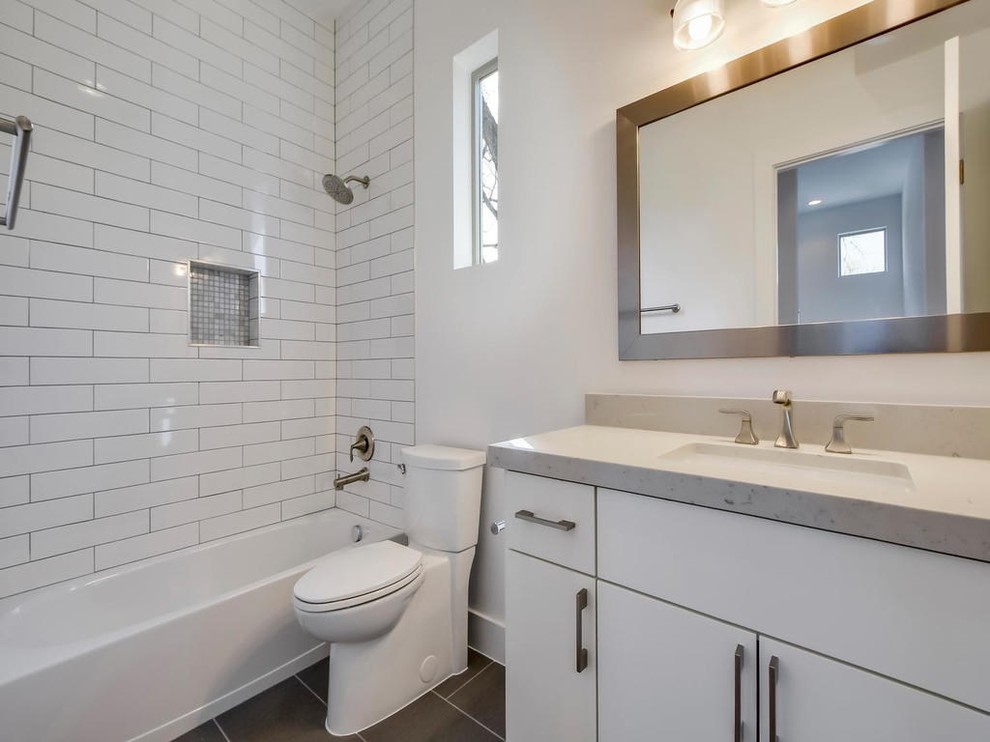 Mid-sized modern 3/4 bathroom in Austin with flat-panel cabinets, white cabinets, an alcove tub, an alcove shower, a two-piece toilet, white tile, subway tile, white walls, porcelain floors, an undermount sink, engineered quartz benchtops, grey floor, a shower curtain and grey benchtops.