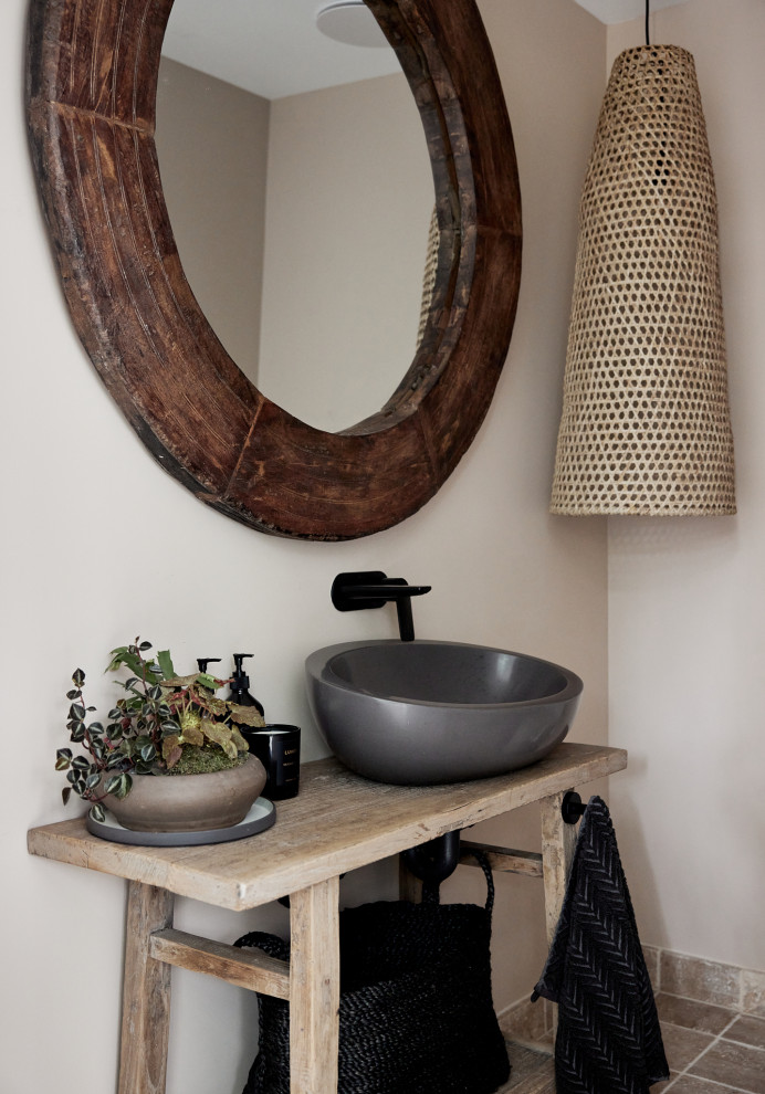 Small beach style powder room in Other with light wood cabinets, beige walls, a vessel sink, wood benchtops, brown floor, brown benchtops and a freestanding vanity.