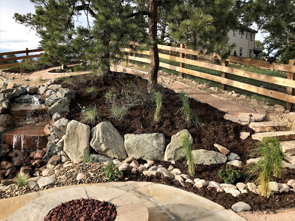Large contemporary backyard full sun xeriscape in Denver with with waterfall.