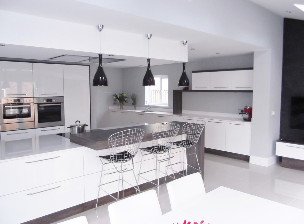 Design ideas for a large contemporary galley open plan kitchen in Other with an integrated sink, flat-panel cabinets, white cabinets, quartzite benchtops, white splashback, stone slab splashback, stainless steel appliances, porcelain floors and with island.