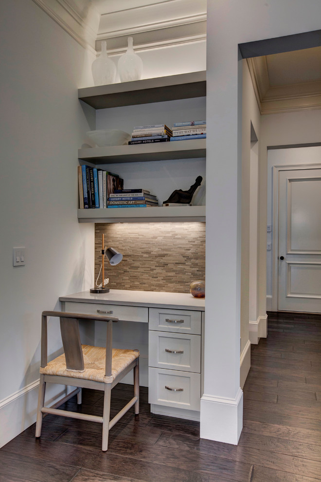 This is an example of a small transitional home office in Orlando with white walls, a built-in desk and dark hardwood floors.