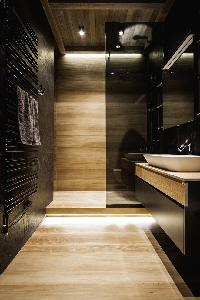 Contemporary 3/4 bathroom in Seattle with a vessel sink, flat-panel cabinets, black cabinets, an alcove shower, black walls and light hardwood floors.