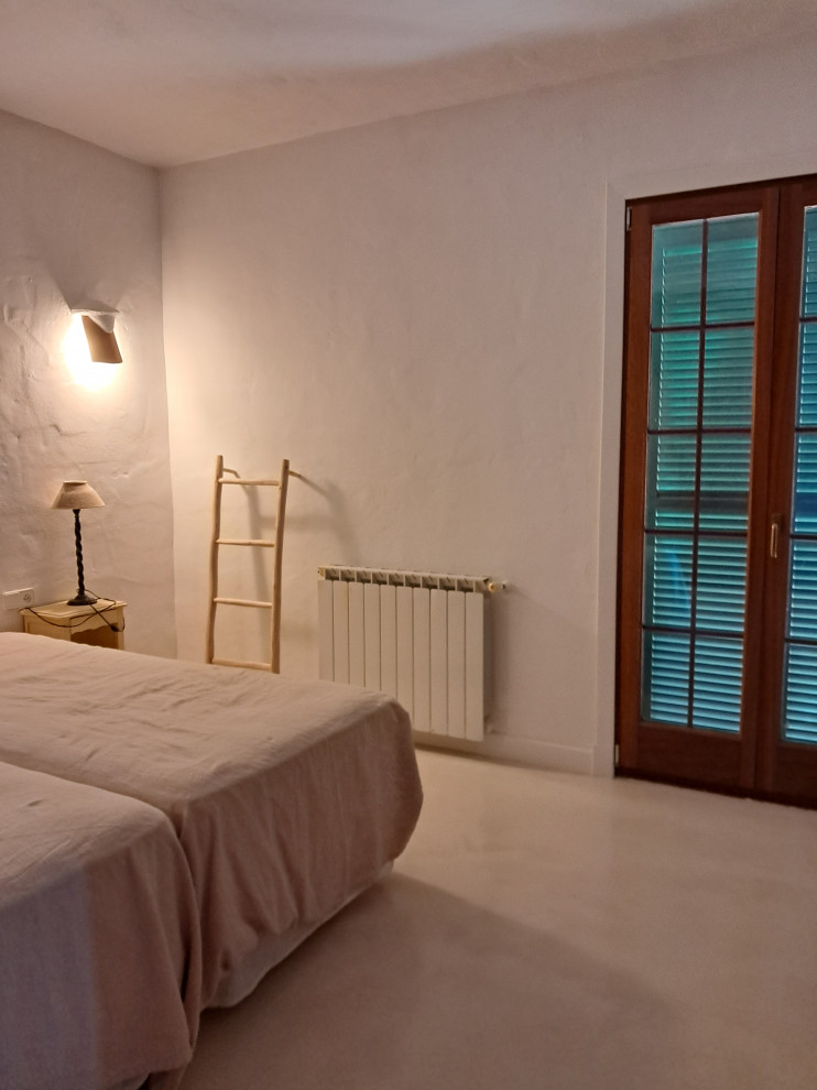 Foto di una piccola camera matrimoniale mediterranea con pareti bianche, pavimento in cemento e pavimento beige