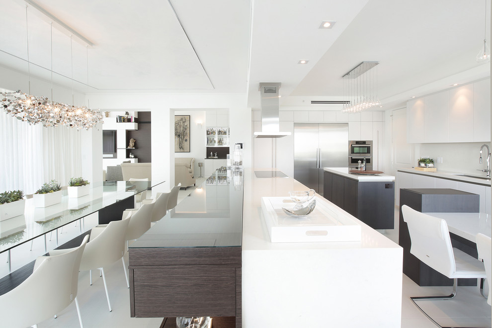 This is an example of a contemporary u-shaped eat-in kitchen in Miami with an undermount sink, flat-panel cabinets, white cabinets, white splashback, stainless steel appliances and with island.