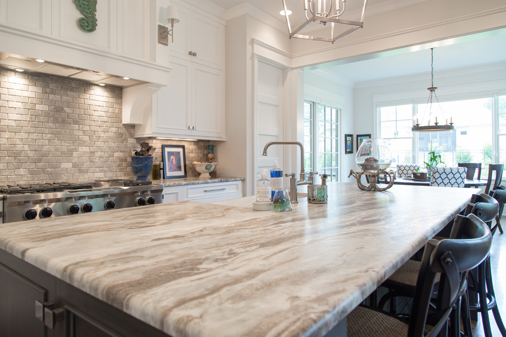 Inspiration for a large transitional l-shaped eat-in kitchen in Charlotte with a farmhouse sink, flat-panel cabinets, white cabinets, quartzite benchtops, brown splashback, stone tile splashback, stainless steel appliances, dark hardwood floors and with island.