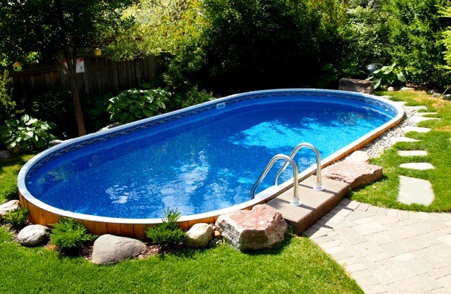 Design ideas for a traditional backyard round aboveground pool in Toronto with concrete pavers.