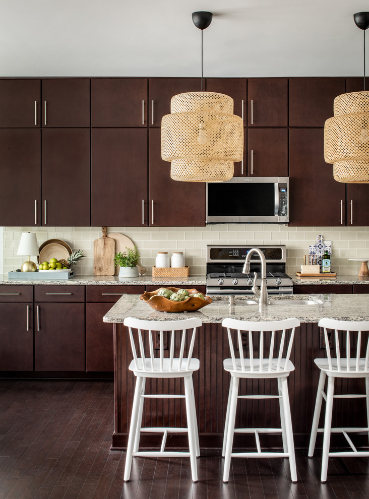 Inspiration for a large beach style kitchen in Raleigh with an undermount sink, flat-panel cabinets, dark wood cabinets, granite benchtops, beige splashback, glass tile splashback, stainless steel appliances, dark hardwood floors, with island, brown floor and beige benchtop.