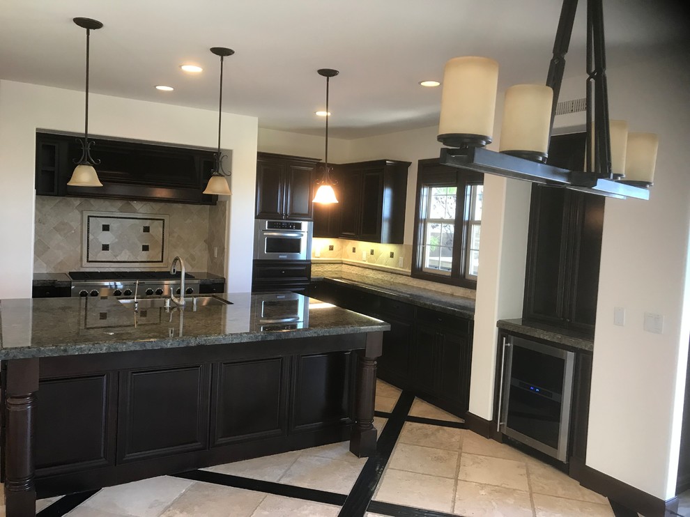 Photo of a mid-sized transitional u-shaped open plan kitchen in Orange County with an undermount sink, recessed-panel cabinets, dark wood cabinets, granite benchtops, beige splashback, stone tile splashback, stainless steel appliances, travertine floors, with island, beige floor and green benchtop.