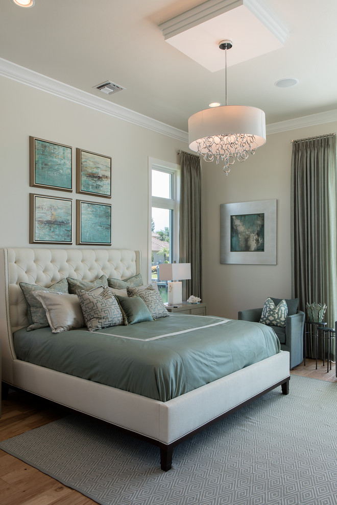 Photo of a large beach style master bedroom in Miami with beige walls and light hardwood floors.