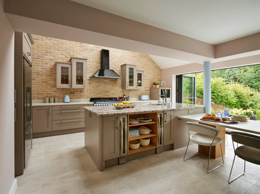 This is an example of a large transitional l-shaped eat-in kitchen in Other with shaker cabinets, with island, an undermount sink, beige cabinets, granite benchtops, brown splashback, brick splashback, black appliances, beige floor and multi-coloured benchtop.