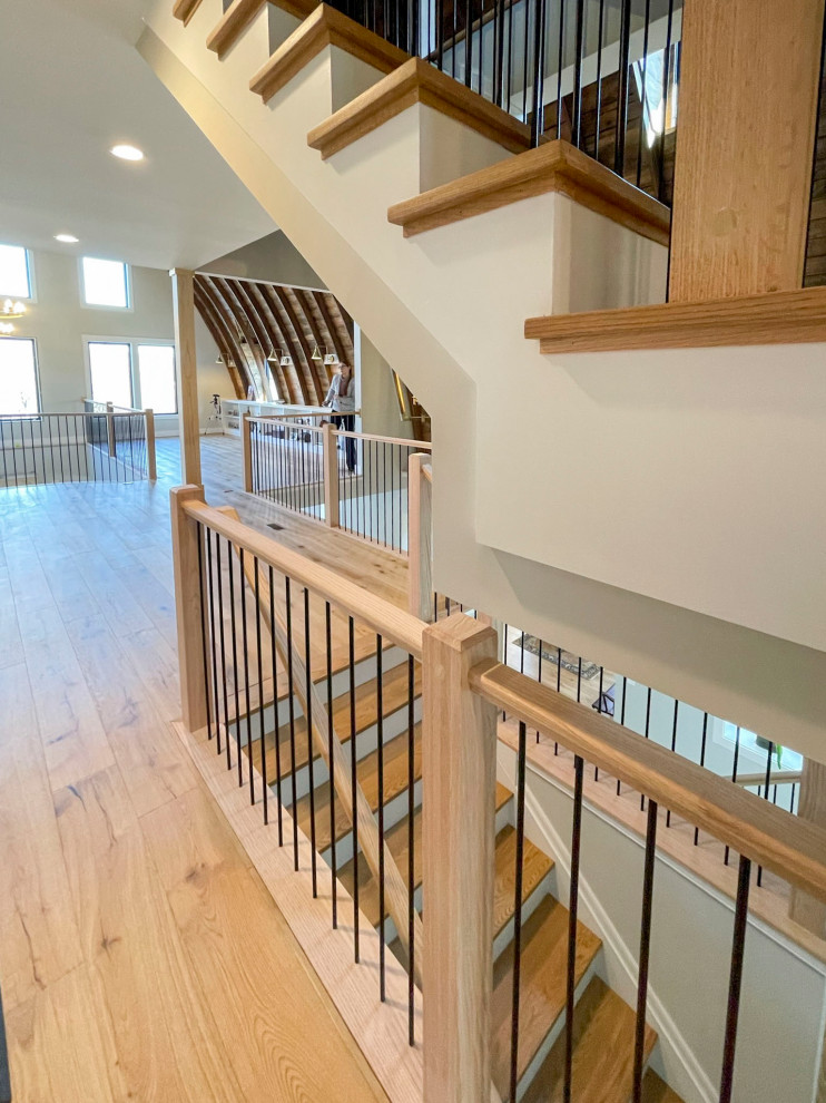 Свежая идея для дизайна: огромная прямая деревянная лестница в стиле неоклассика (современная классика) с деревянными ступенями и перилами из смешанных материалов - отличное фото интерьера