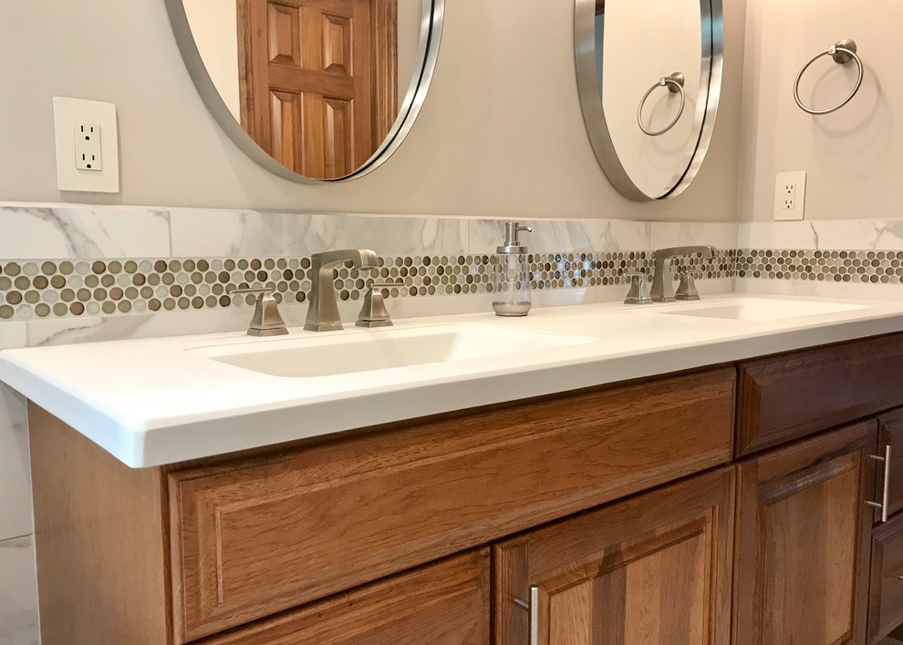 Freestanding bathtub - mid-sized transitional master gray tile and porcelain tile porcelain tile and gray floor freestanding bathtub idea with medium tone wood cabinets, beige walls, an integrated sink, raised-panel cabinets, white countertops, solid surface countertops and a hinged shower door
