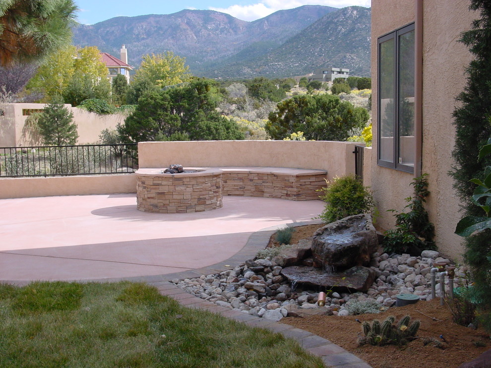 Photo of a large traditional courtyard partial sun formal garden for spring in Albuquerque with concrete pavers and a fire feature.