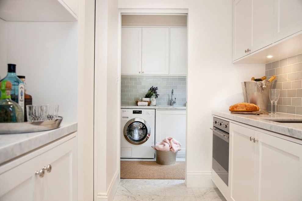 This is an example of a mid-sized transitional galley utility room in Sydney with an undermount sink, beaded inset cabinets, white cabinets, marble benchtops, white walls, medium hardwood floors and a side-by-side washer and dryer.