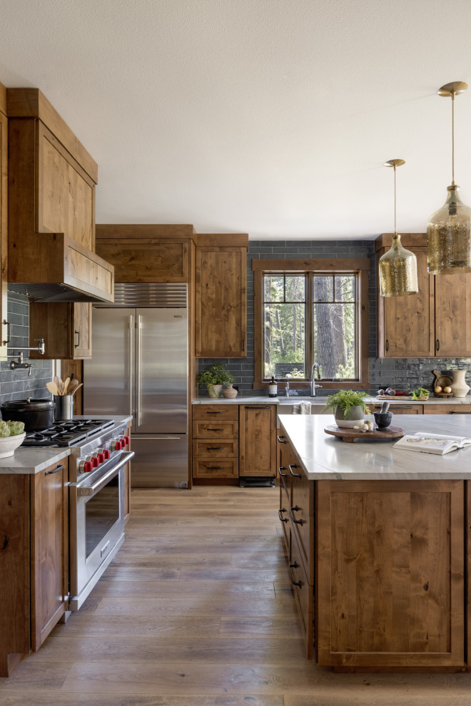 Bild på ett mellanstort funkis grå grått kök, med en undermonterad diskho, skåp i shakerstil, skåp i mellenmörkt trä, granitbänkskiva, svart stänkskydd, stänkskydd i tunnelbanekakel, rostfria vitvaror, mellanmörkt trägolv och en köksö
