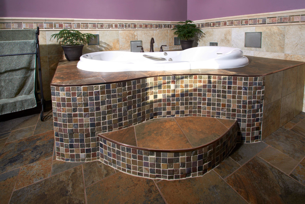 Inspiration for a large mediterranean master bathroom in Other with an undermount sink, granite benchtops, a drop-in tub, a two-piece toilet, brown tile, porcelain tile, purple walls, raised-panel cabinets, brown cabinets, a corner shower and slate floors.
