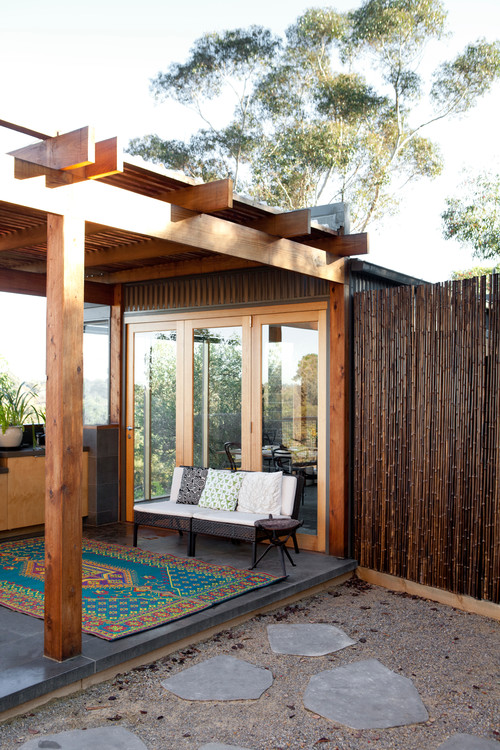 A tall mahogany stained bamboo privacy wall that shades this lovely patio from any neighbor's eyes. The rich dark stain matches the rest of the wooden roof and supports of the patio.