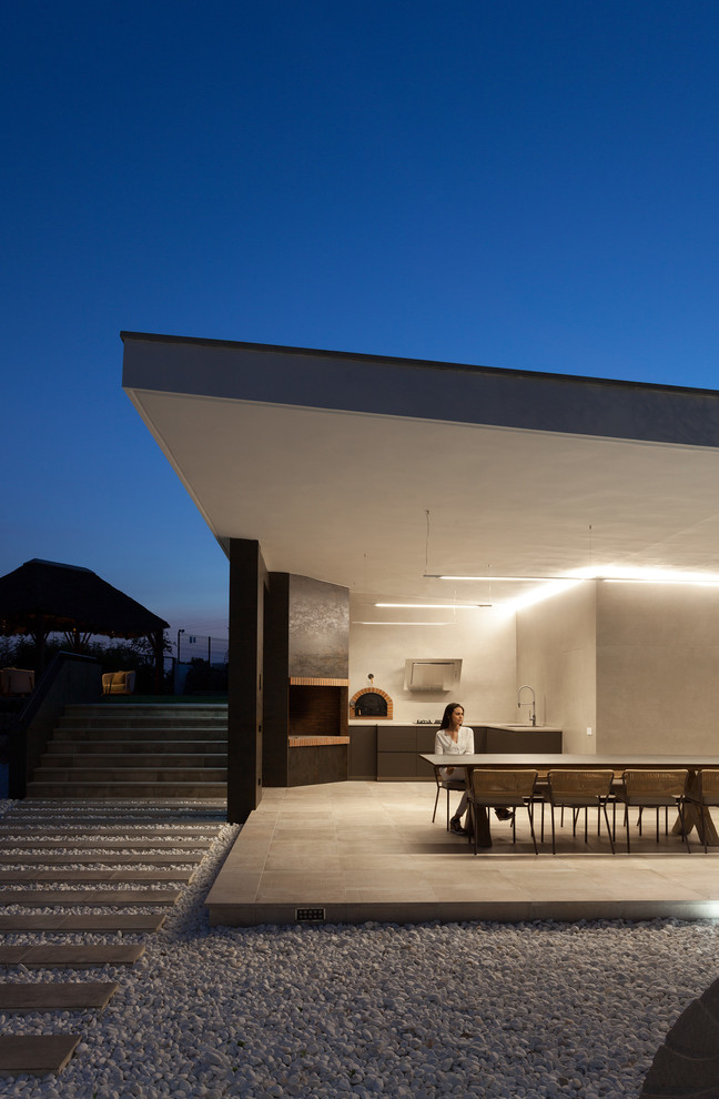 Modelo de terraza moderna en anexo de casas con cocina exterior y suelo de baldosas
