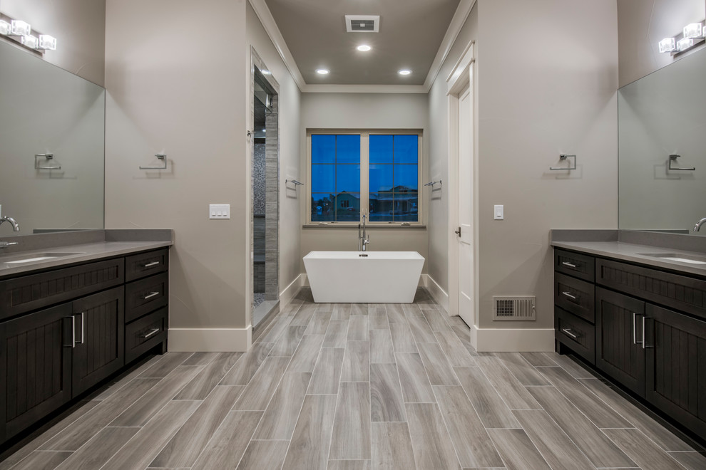 Inspiration for a large classic ensuite wet room bathroom in Denver with shaker cabinets, dark wood cabinets, a freestanding bath, grey tiles, porcelain tiles, grey walls, porcelain flooring, a submerged sink, quartz worktops, grey floors, a hinged door and grey worktops.