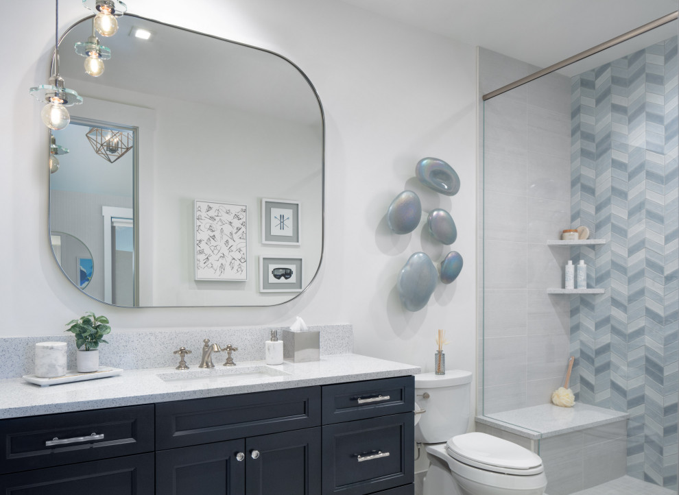 Kids' Girls' Bathroom with Blue Tile - This adorable kids' bathroom features herringbone shades of blue tile in the shower, silver accents, and a navy blue vanity. Cute floral glass pendants hang above the vanity, and ski artwork along with blue glass orbs adorn the walls.