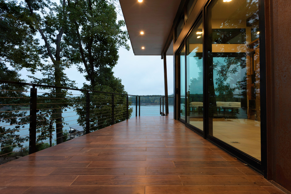 Inspiration pour une terrasse latérale et au premier étage minimaliste de taille moyenne avec des solutions pour vis-à-vis, une extension de toiture et un garde-corps en métal.