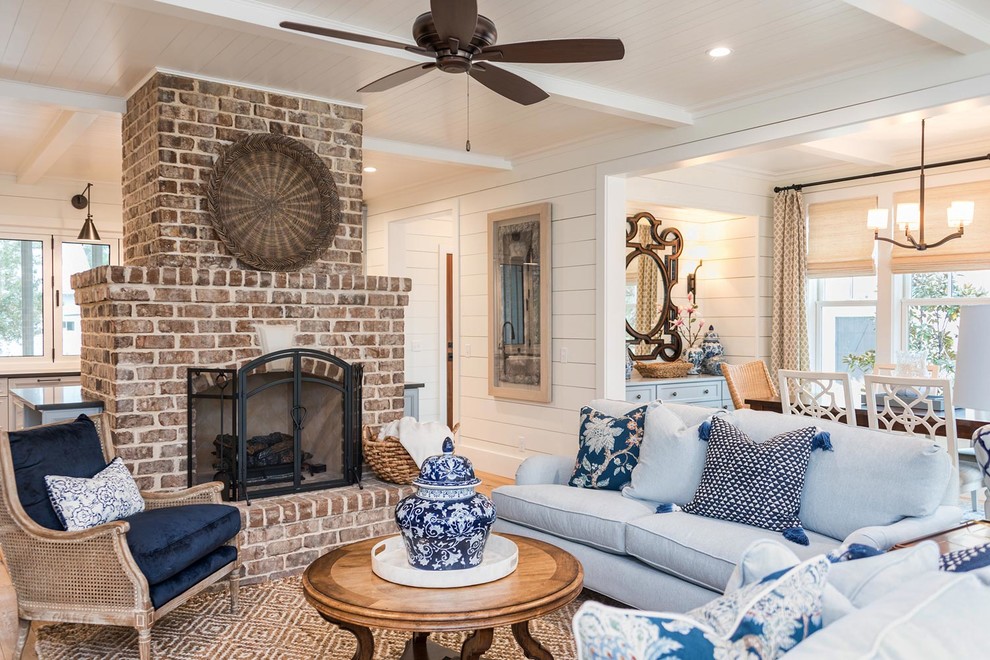 Inspiration for a large beach style open concept living room in Atlanta with white walls, light hardwood floors, a standard fireplace, a brick fireplace surround, a wall-mounted tv and brown floor.