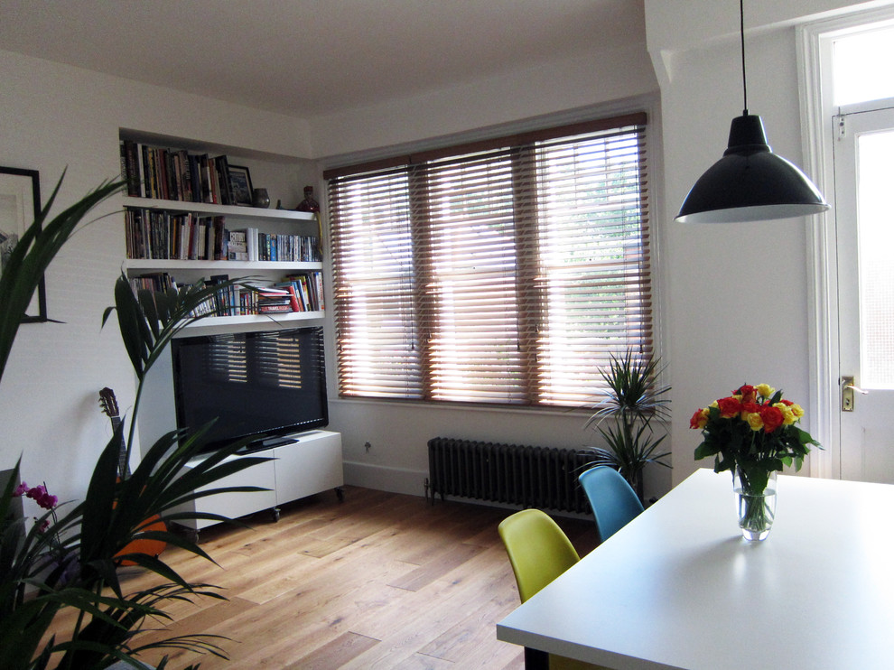 This is an example of a medium sized contemporary open plan living room in London with a reading nook, white walls, no fireplace, a plastered fireplace surround and a built-in media unit.