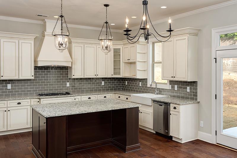 Large traditional u-shaped eat-in kitchen in Atlanta with a farmhouse sink, white cabinets, granite benchtops, grey splashback, dark hardwood floors, with island, glass tile splashback and recessed-panel cabinets.