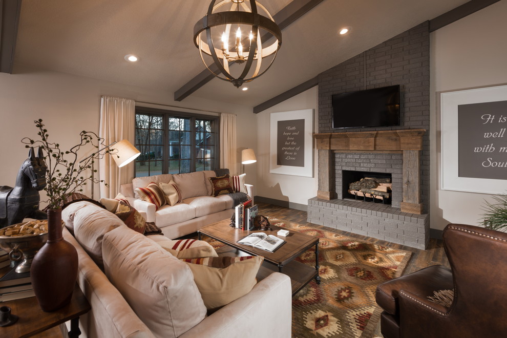 This is an example of a large country open concept living room in Other with grey walls, medium hardwood floors, a standard fireplace, a wood fireplace surround, a wall-mounted tv and brown floor.