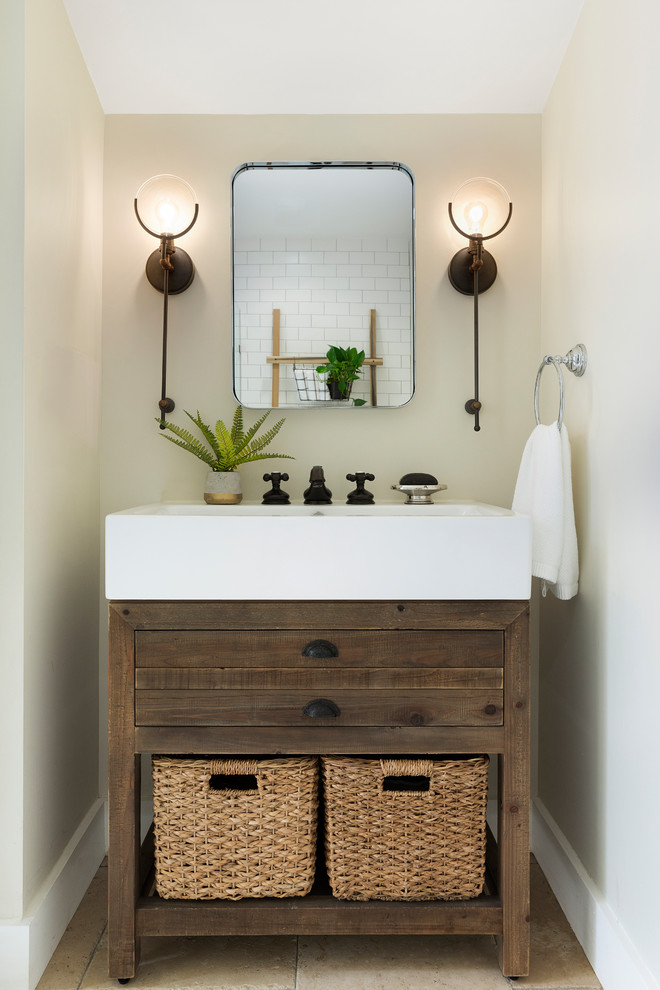 Design ideas for a mid-sized country powder room in Minneapolis with flat-panel cabinets, dark wood cabinets, beige walls, travertine floors, an integrated sink and brown floor.