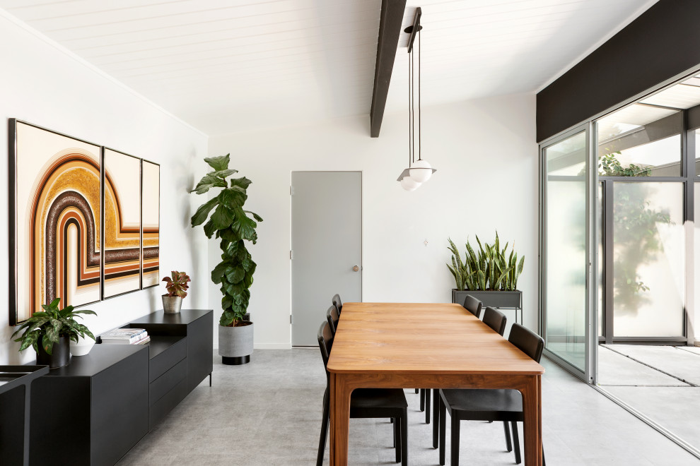 Inspiration for a midcentury dining room in San Francisco with white walls and grey floor.