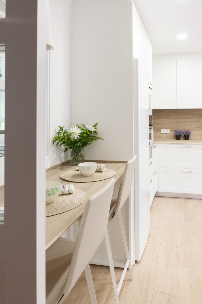 Mid-sized contemporary u-shaped separate kitchen in Madrid with a drop-in sink, beaded inset cabinets, white cabinets, quartz benchtops, brown splashback, engineered quartz splashback, white appliances, porcelain floors, brown floor and brown benchtop.