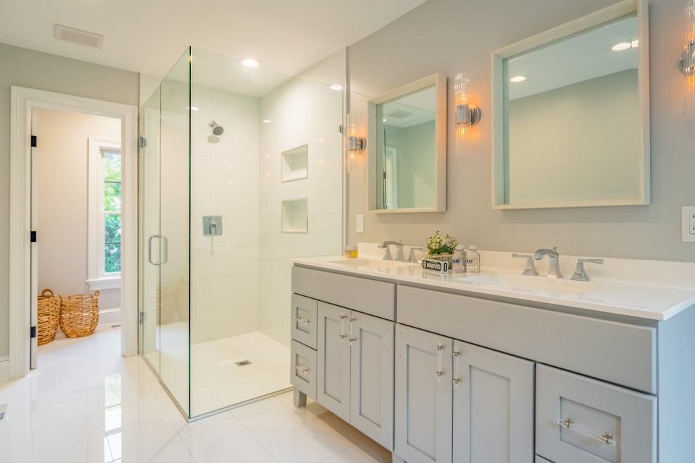 Photo of a mid-sized country master bathroom in New York with recessed-panel cabinets, grey cabinets, a freestanding tub, a corner shower, a two-piece toilet, grey walls, marble floors, an undermount sink, white floor, a hinged shower door and white benchtops.