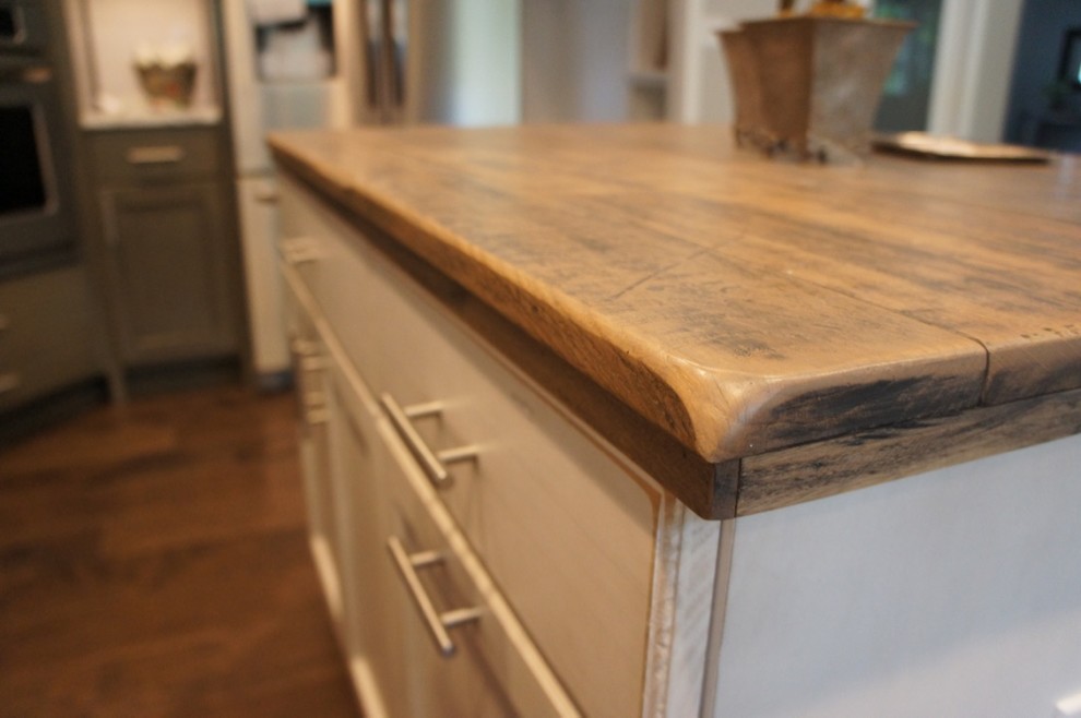 Example of a transitional u-shaped eat-in kitchen design with flat-panel cabinets, white backsplash, stainless steel appliances and an island