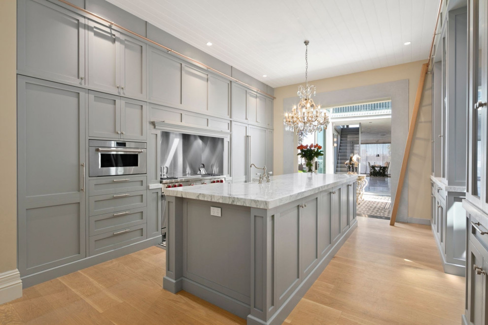 Design ideas for a transitional separate kitchen in Sydney with a farmhouse sink, shaker cabinets, grey cabinets, marble benchtops, metallic splashback, panelled appliances, medium hardwood floors, with island, brown floor, multi-coloured benchtop and timber.
