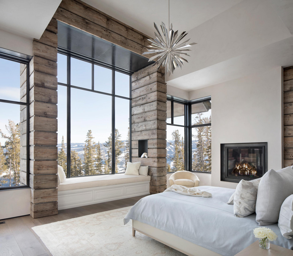 This is an example of a rustic master bedroom in Other with white walls, medium hardwood flooring and a standard fireplace.