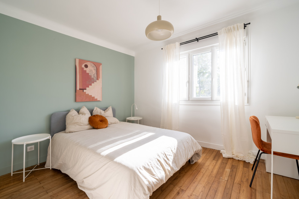 Ejemplo de habitación de invitados actual de tamaño medio con paredes verdes, suelo de madera en tonos medios y suelo marrón
