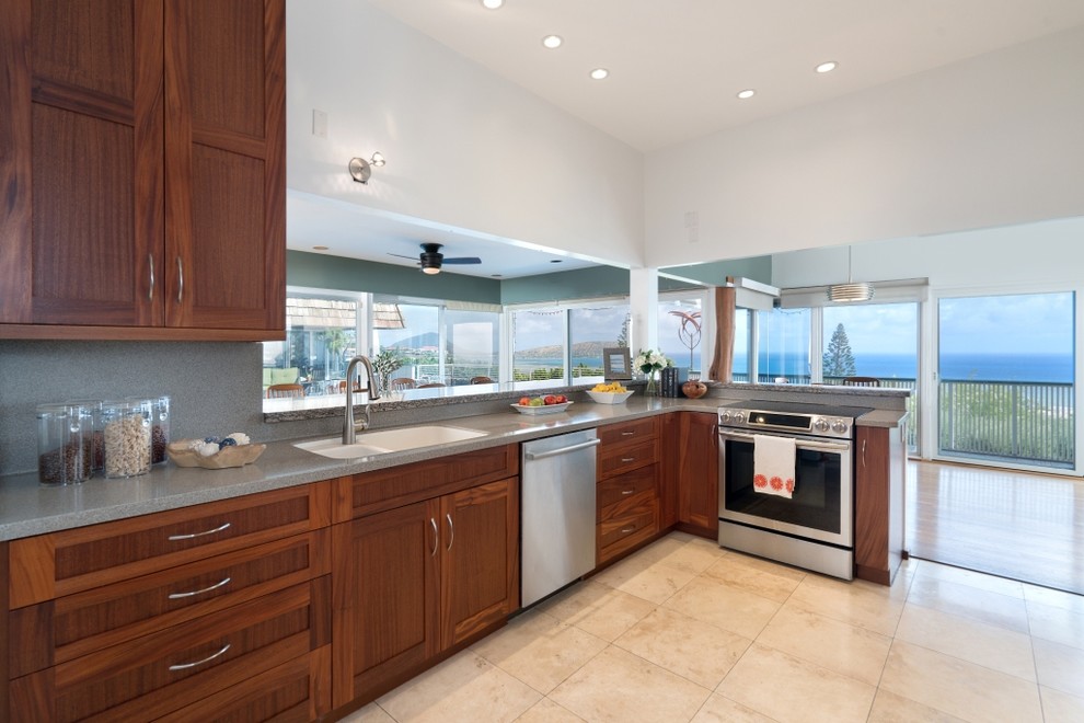 Inspiration for a large tropical l-shaped eat-in kitchen in Hawaii with shaker cabinets, medium wood cabinets, stainless steel appliances, no island, an undermount sink, granite benchtops, grey splashback, stone slab splashback, ceramic floors and beige floor.