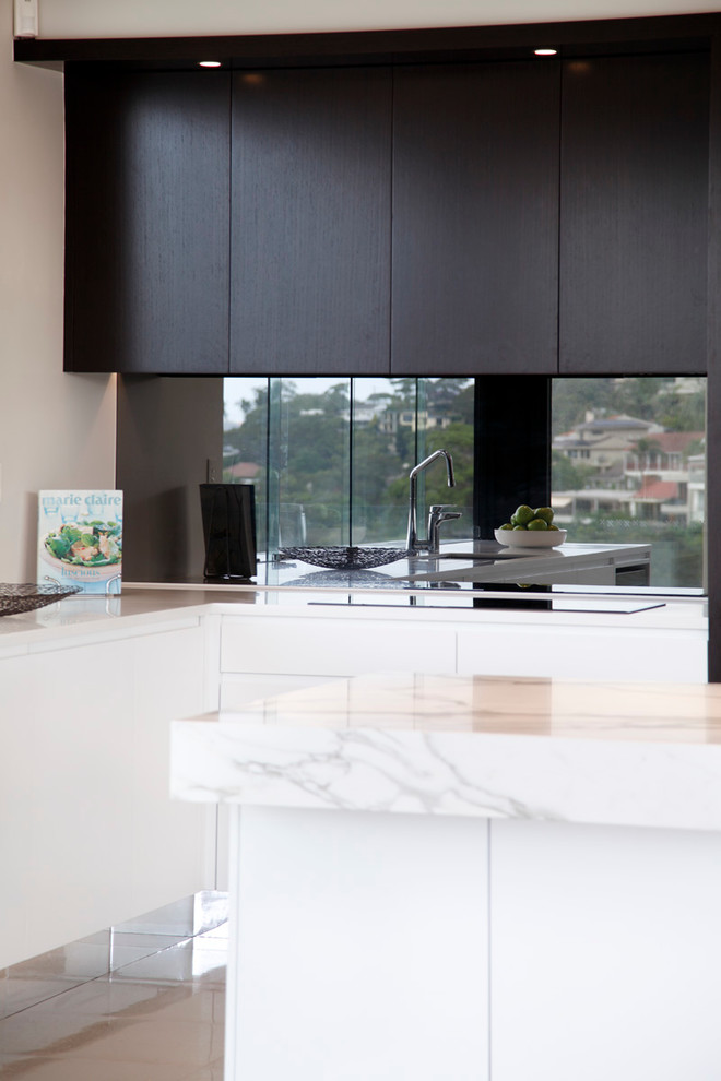 Photo of a mid-sized modern l-shaped separate kitchen in Sydney with an undermount sink, flat-panel cabinets, black cabinets, marble benchtops, metallic splashback, glass sheet splashback, stainless steel appliances, porcelain floors and with island.