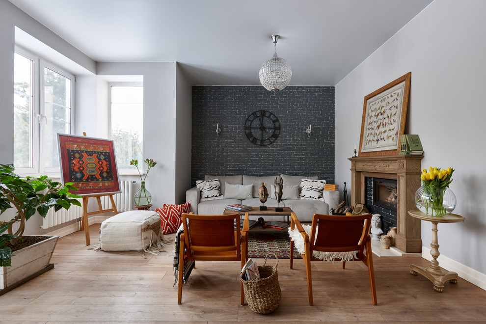 This is an example of an eclectic open concept living room in Moscow with medium hardwood floors, a standard fireplace, brown floor, black walls, a brick fireplace surround and no tv.