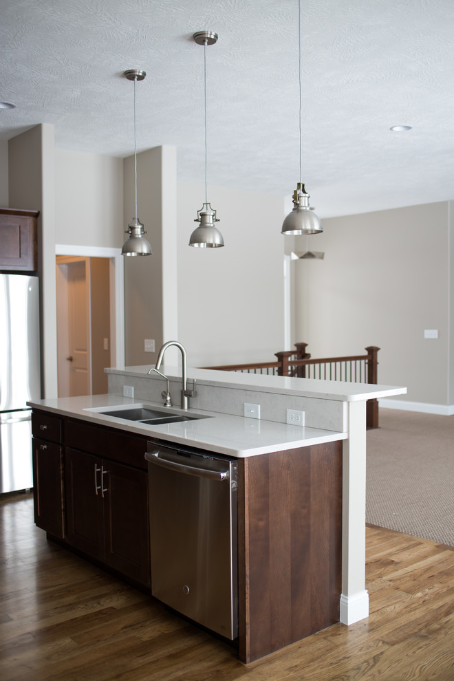Inspiration for a mid-sized transitional l-shaped dark wood floor enclosed kitchen remodel with a double-bowl sink, shaker cabinets, dark wood cabinets, quartz countertops, gray backsplash, stone tile backsplash, stainless steel appliances and an island
