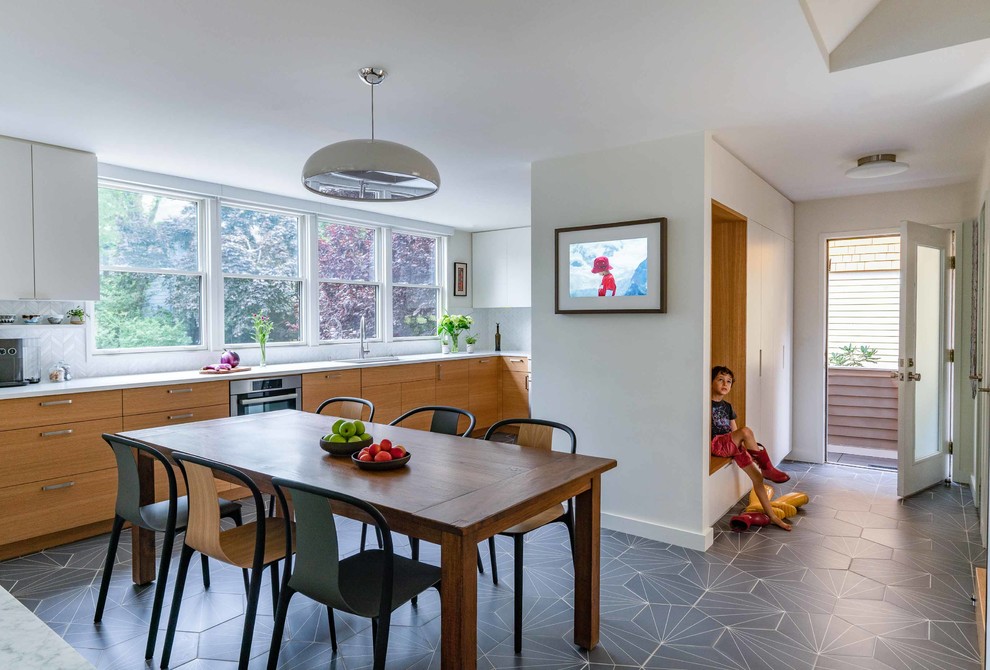 This is an example of a midcentury kitchen/dining combo in New York with white walls, porcelain floors and grey floor.