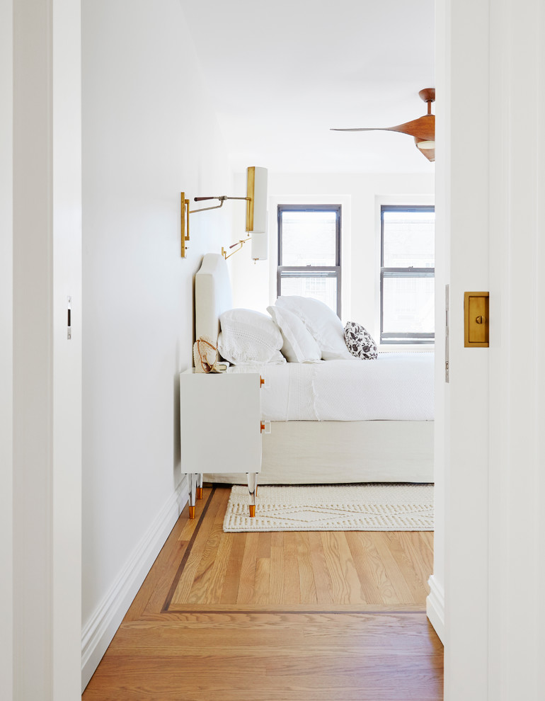 Inspiration for a mid-sized contemporary master bedroom in New York with white walls, medium hardwood floors and no fireplace.